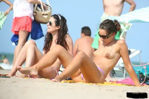 2 topless girls at the beach in thongs