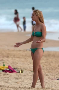 Sexy brunette in thong bikini and blonde friend in green bikini at the beach