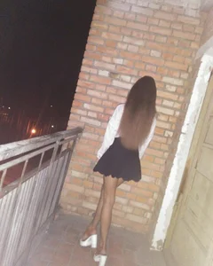 Skinny Girl in a Short Skirt, Pantyhose and on Heels Standing on the Apartment Building Balcony Candid Photo