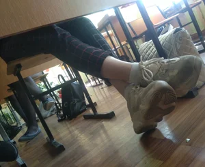 Skinny Legs in Sneakers And Socks Under Table Closeup Photo