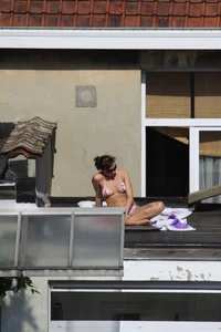 Neighbor on rooftop tanning in bikinis