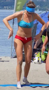 Skinny mature lady in red bikini bottom on the beach playing volleyball