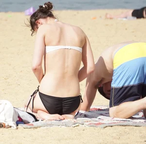 Sexy girl on the beach laying out and bending over in her bikini