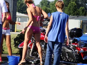 Group of cute girls at a car wash in bikinis and shorts