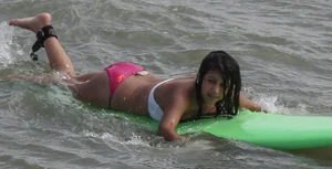 Brunette bikini girl on the beach and surfing in her bikini