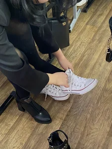 College Candid Teen in Pantyhose And a Skirt Putting On Her Sneakers in Classroom