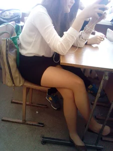 College Teen in Pantyhose and a Skirt Sitting at a Desk With Crossed Legs