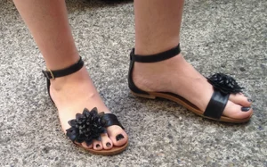 Feet in sandals with toenails painted black closeups