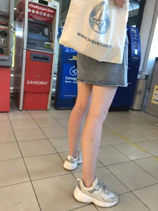 Young Candid Girl With Slim Pale Legs In a Denim Skirt Waiting in the Queue