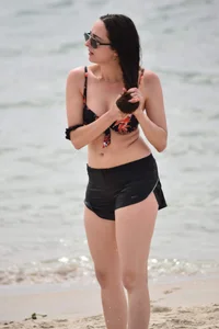 Brunette girl in black shorts and bikini top on the beach