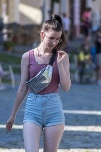 Sexy brunette chick with glasses in denim overalls showing her cheeks