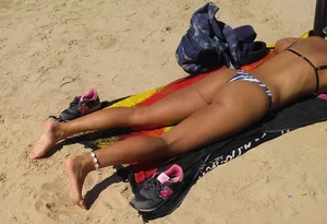 Sexy girl getting some sun laying on the beach in thong bikini
