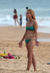 Sexy brunette in thong bikini and blonde friend in green bikini at the beach