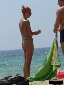 Topless skinny blonde lady in a g-string bikini at the beach