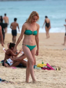 Sexy brunette in thong bikini and blonde friend in green bikini at the beach