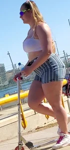 Chubby girl in a top and shorts with a scooter street photo