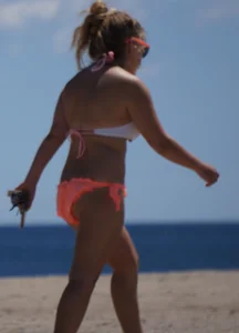 Thick blonde girl in an orange bikini on the beach