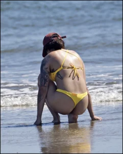 Sexy tattooed beach brunette with a great ass in yellow thong bikini