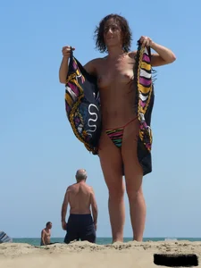 Topless beach milf looking sexy in a tiny g-string bikini