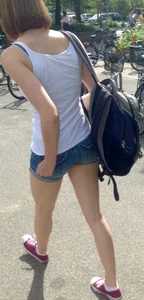 Nice petite booty and long slim legs wearing denim shorts, candid girl with a backpack walking down the street