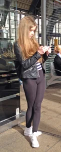 Cute Young Girl in Tights Standing With Crossed Legs at a Station