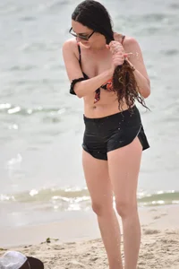 Brunette girl in black shorts and bikini top on the beach