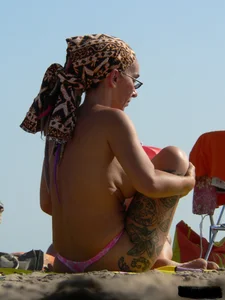 Topless tattooed lady at the beach with a nice ass in pink thong bikini