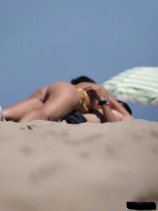 Topless lady on the beach in a gold thong with a nice ass