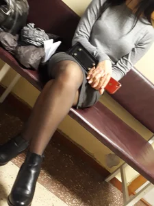 Girl in a Skirt and Black Pantyhose Sitting Cross-Legged on the Bench