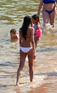 Skinny brunette girl on the beach in black and white bikini