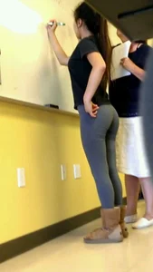 Teen candid girl in grey tights writing on marker board in class