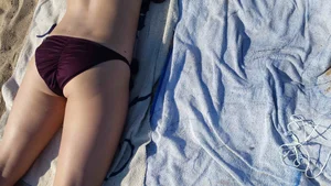 Hot girl laying on the beach in her purple bikini