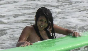 Brunette bikini girl on the beach and surfing in her bikini