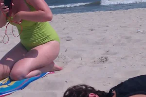 Redhead laying on the beach in green swimsuit