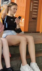A Hot Teen Candid Girl in Blue Denim Shorts And Sneakers Sitting on the Step of the Stairs, Long Skinny Legs