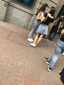 Hot slim legs closeups, street girl wearing a denim fringed skirt