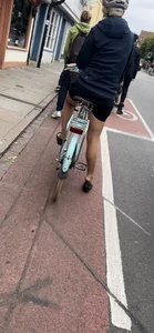 Girl on a bike wearing pantyhose, skirt and flats standing with her shoe half taken off