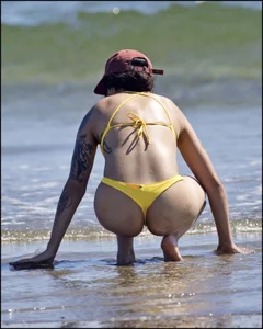 Sexy tattooed beach brunette with a great ass in yellow thong bikini