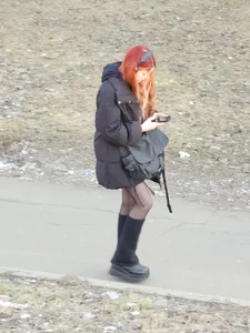 Cute ginger girl wearing knee-high boots and black pantyhose on the street in winter creepshot
