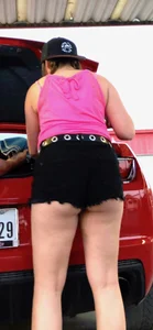 Girl showing her ass cheeks at her car in black shorts