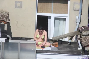 Neighbor on rooftop tanning in bikinis