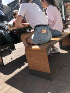 Candid girl in denim shorts sitting in a street cafe