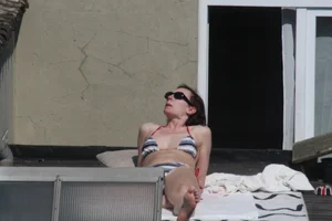 Neighbor on rooftop tanning in bikinis