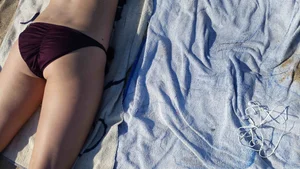 Hot girl laying on the beach in her purple bikini