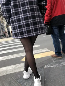 Cute candid girl with legs in black pantyhose waiting on the crosswalk