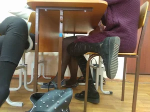 Girl With Skinny Legs in Black Pantyhose Sitting at the Desk With Soles of Her Shoes Showing