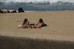 Two babes laying on the beach in bikinis with nice asses
