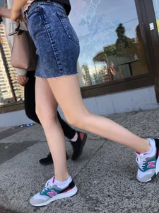 Cute Girl in a Short Denim Skirt Walking on a Street And Waiting on a Crosswalk Gallery