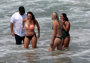 Big boobed babe with pokies in a bikini on the beach with friends