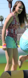 Brunette skinny teen in green shorts playing in a bounce house